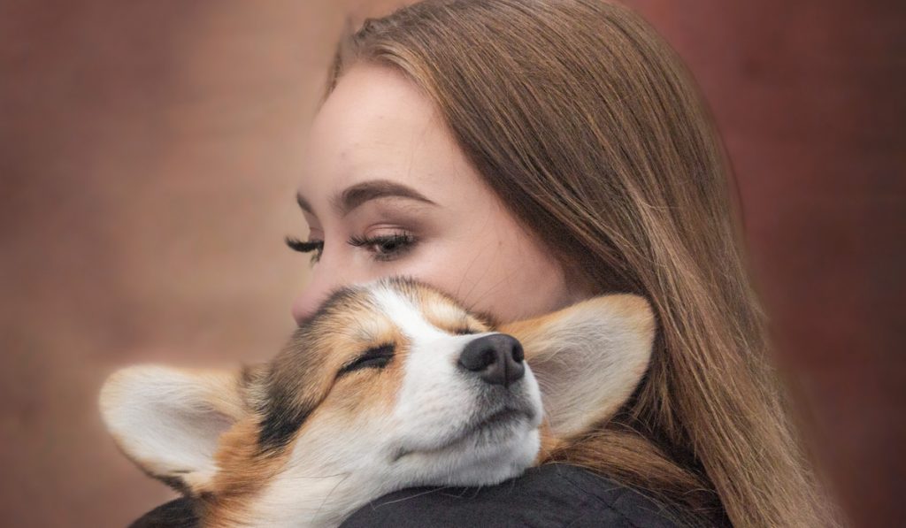 girl cuddling corgi