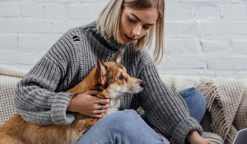 girl sitting on sofa with corgi